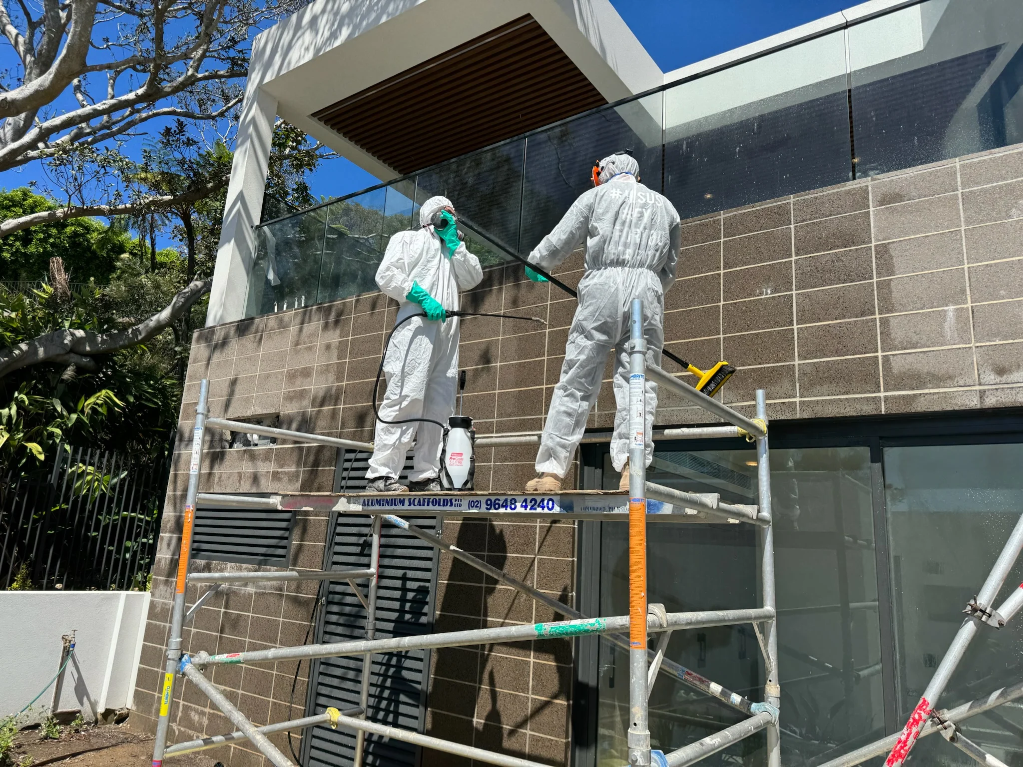 ProLux applicators in protective gear coating a wall from scaffolding in Sydney
